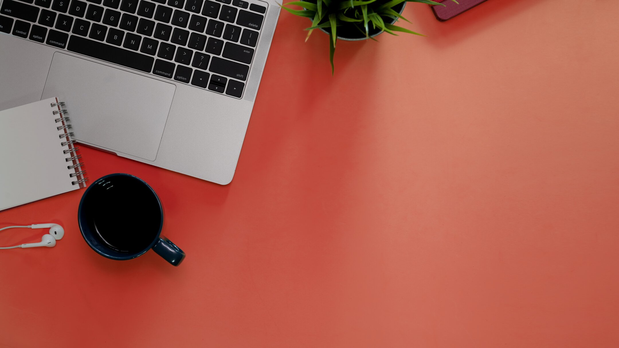 Office desk table with office supplies and laptop on orange background